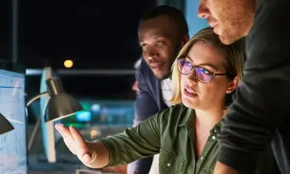 Three employees looking at a screen